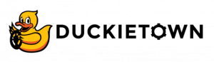 The logo of Duckietown shows a friendly cartoonish duck, Mack, smiling and holding a steering wheel. The text reads "Duckietown"